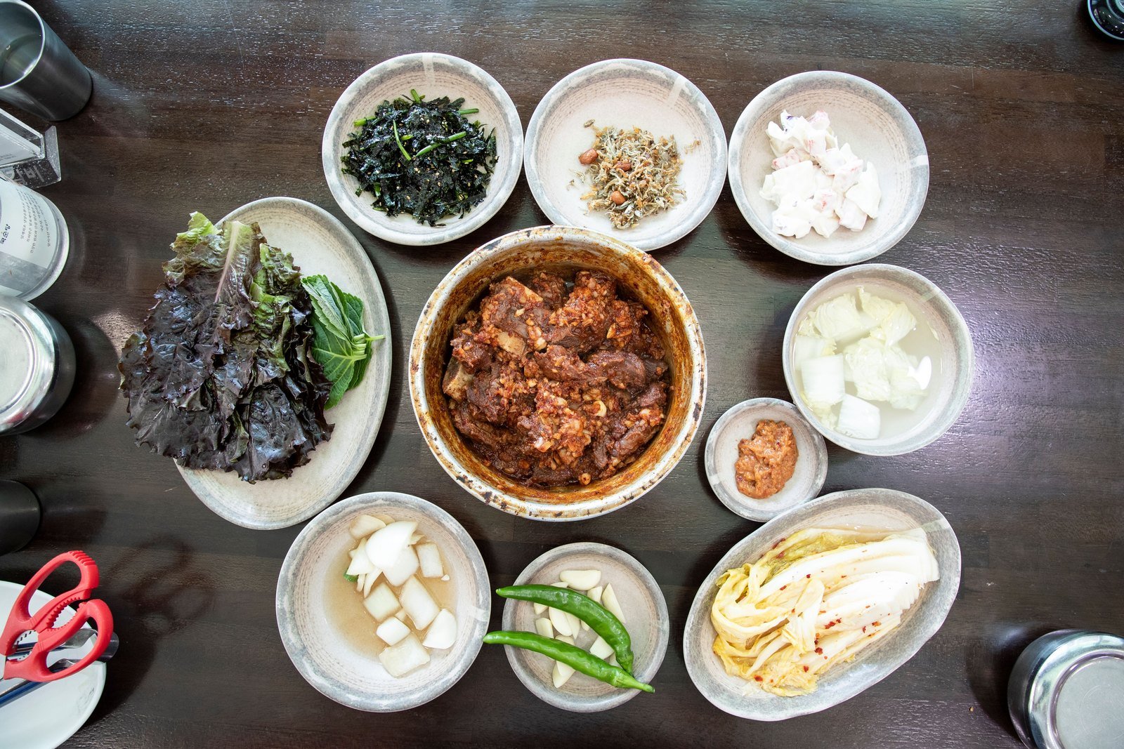 A Dongin-dong jjimgalbi table: braised short ribs in a metal bowl with side dishes