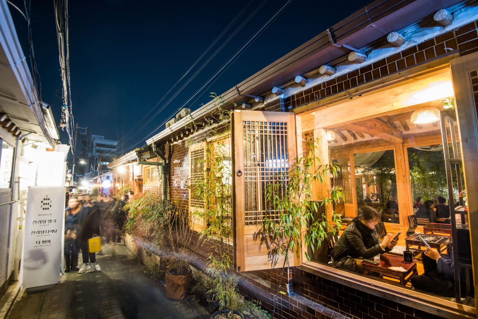 A hanok café rebuilt with glass walls, at night. Most Ikseon-dong cafés keep their lights on until around 10 p.m.