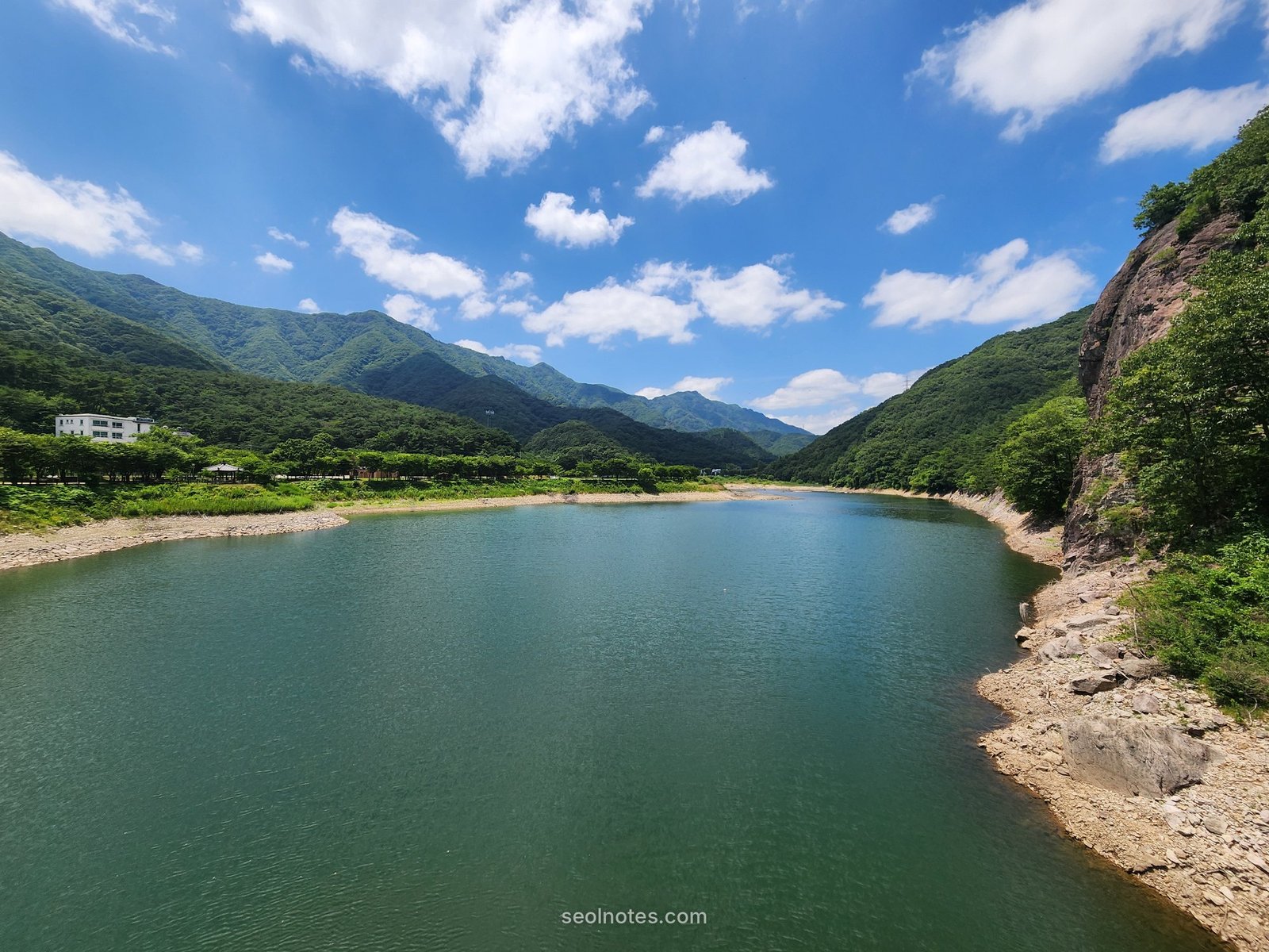 Wide view of a mountain reservoir with a rocky cliff on the right