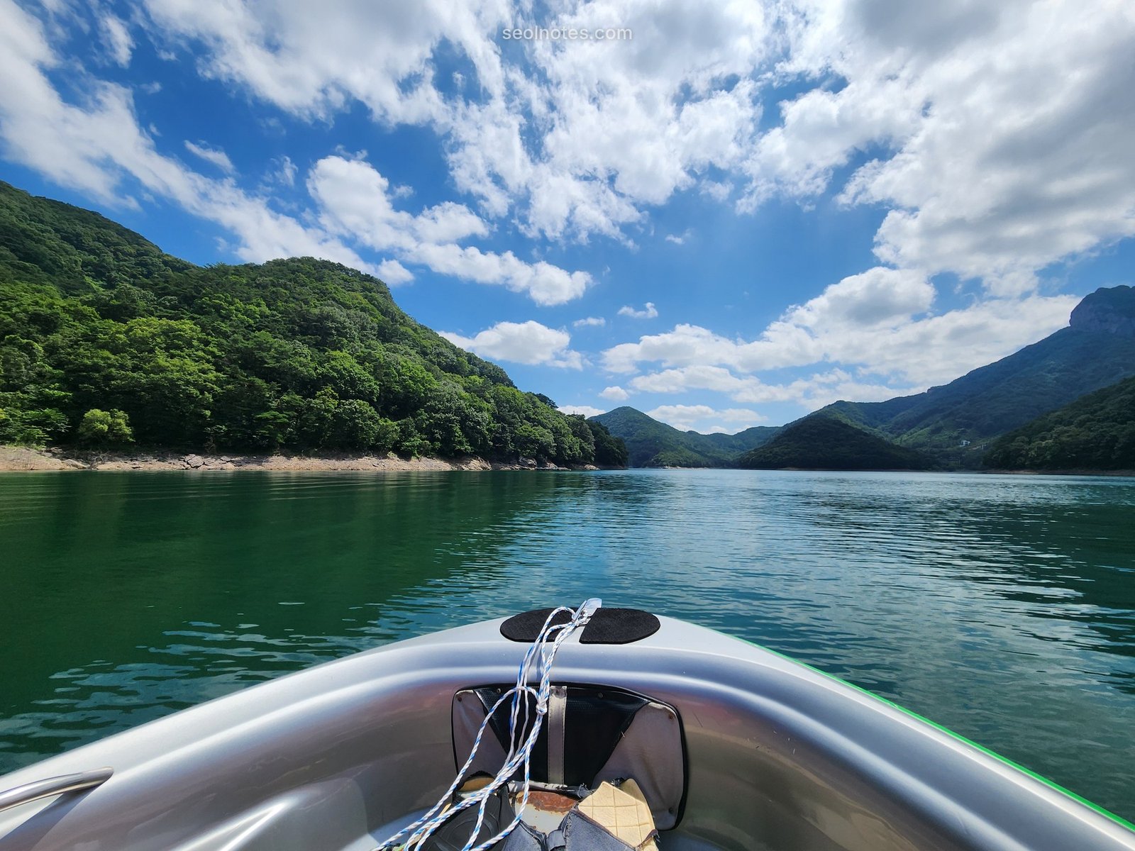 View from the bow of a boat on a green mountain lake